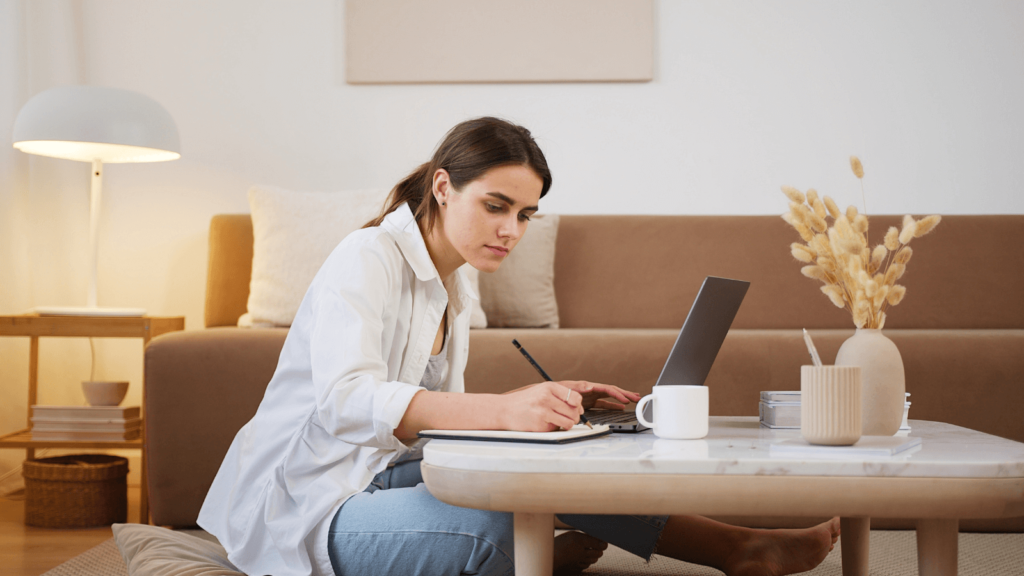 Frau, die am Laptop sitzt und sich Notizen macht