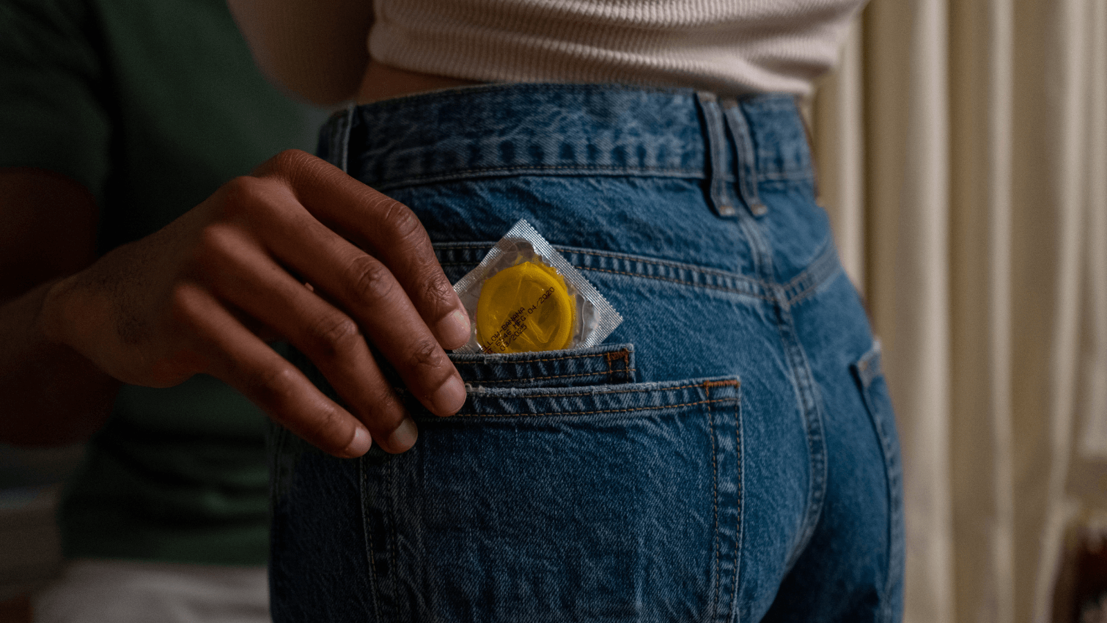 Hand, die Kondom aus Hosentasche zieht