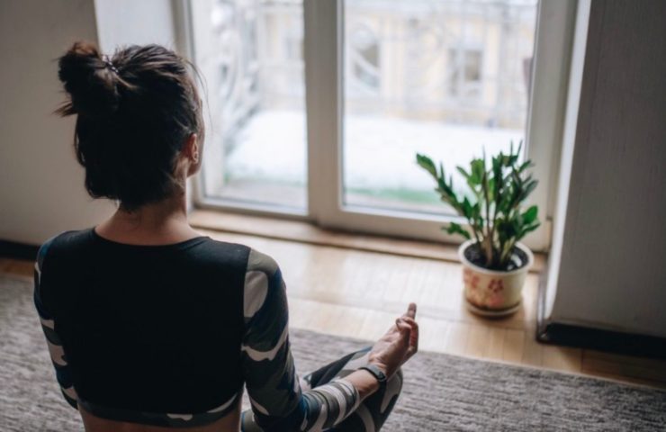 Frau, die vor dem Fenster meditiert