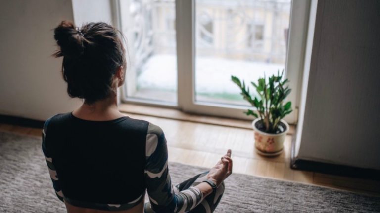 Frau, die vor dem Fenster meditiert