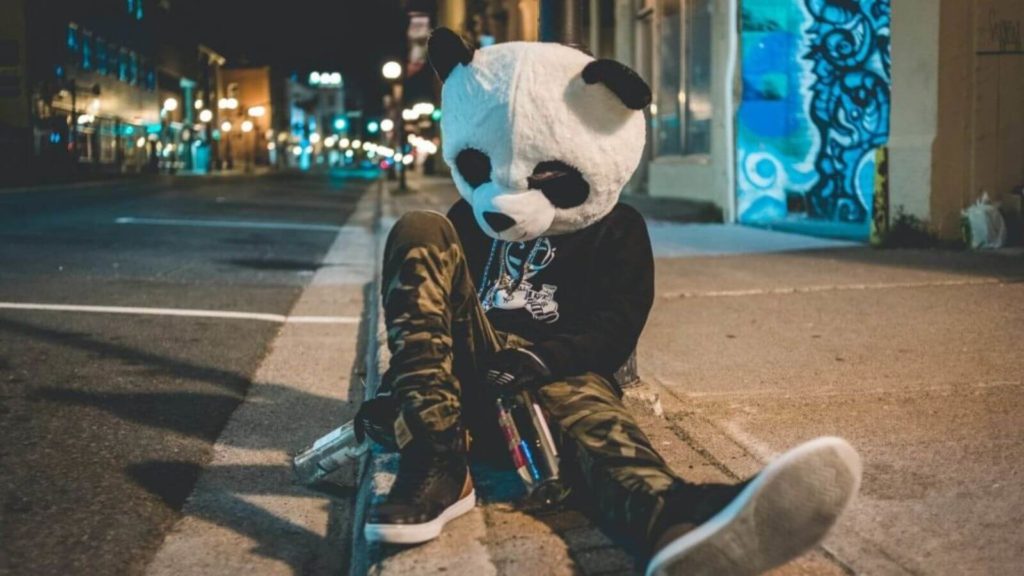 Betrunkener, der im Panda Kostüm auf der Straße sitzt