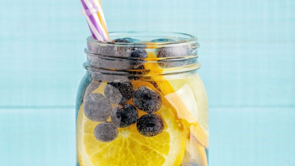 Glas mit Mineralwasser, Zitronen und Blaubeeren