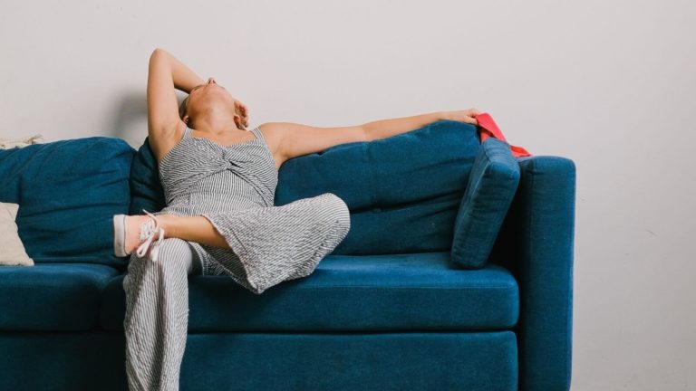 Frau, die erschöpft auf dem Sofa sitzt