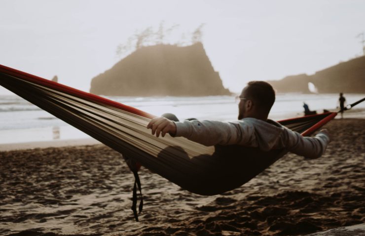 Junger Mann, der am Strand in einer Hängematte liegt