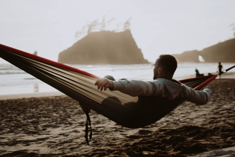 Junger Mann, der am Strand in einer Hängematte liegt