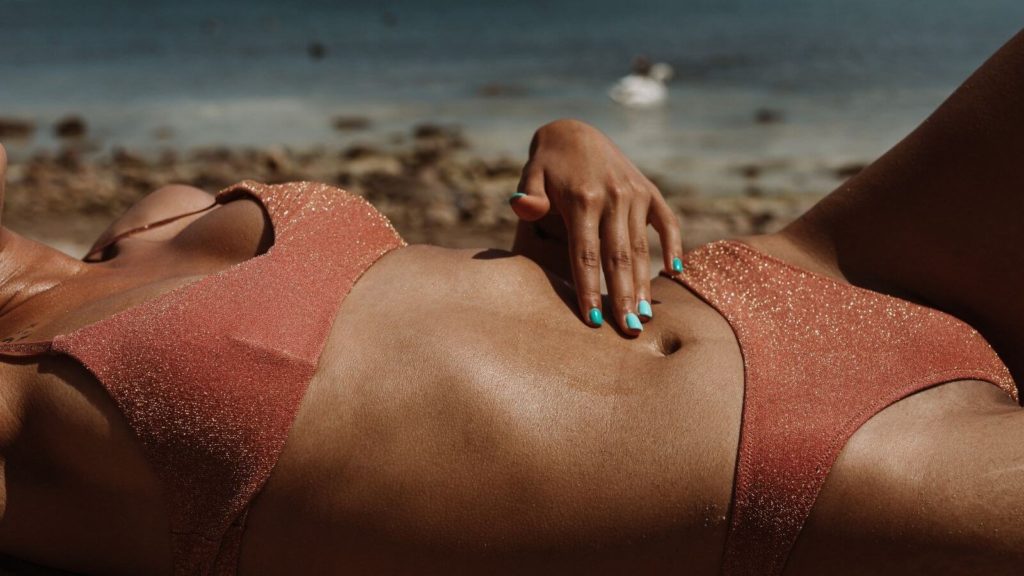 Frau, die im Bikini am Strand liegt