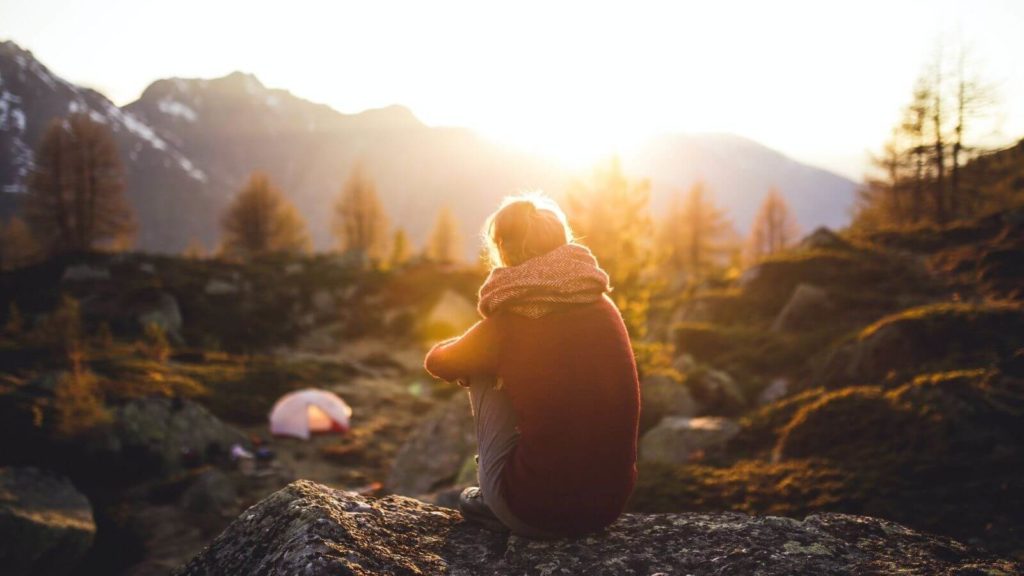 Frau, die sich draußen den Sonnenaufgang ansieht