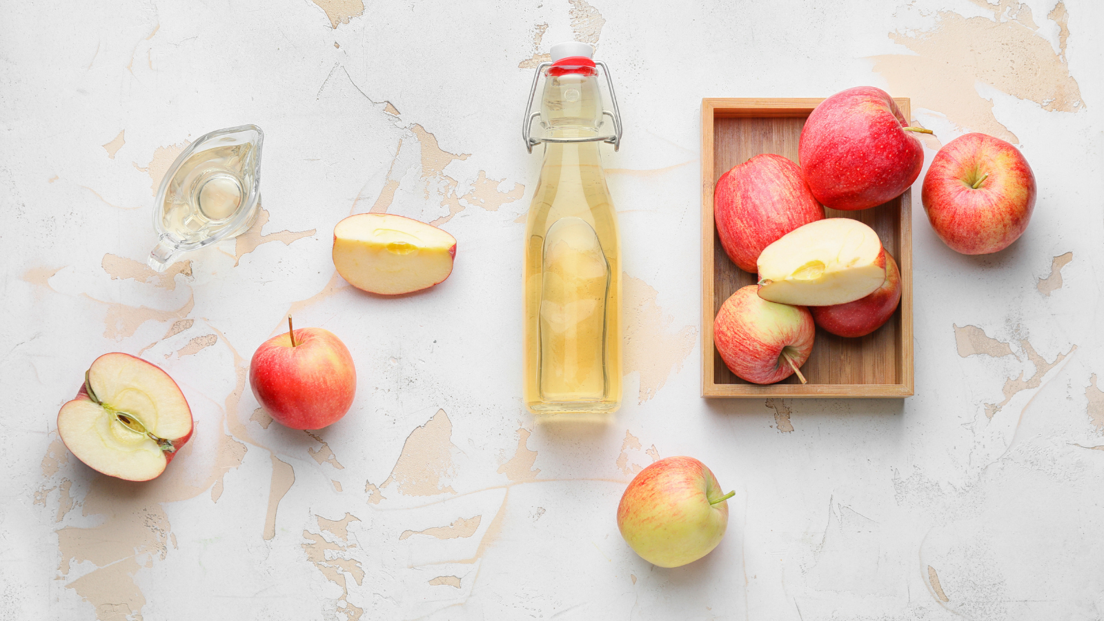Flasche mit Apfelessig und ganzen und halbierten Äpfeln