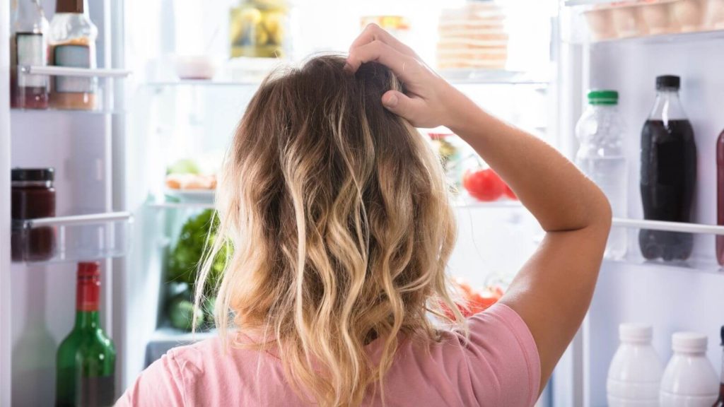 Frau steht vor dem Kühlschrank