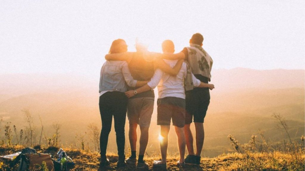 Vier Freunde schauen auf die bergige Landschaft. Soziale Netzwerke sind wichtig für eine starke Resilienz.